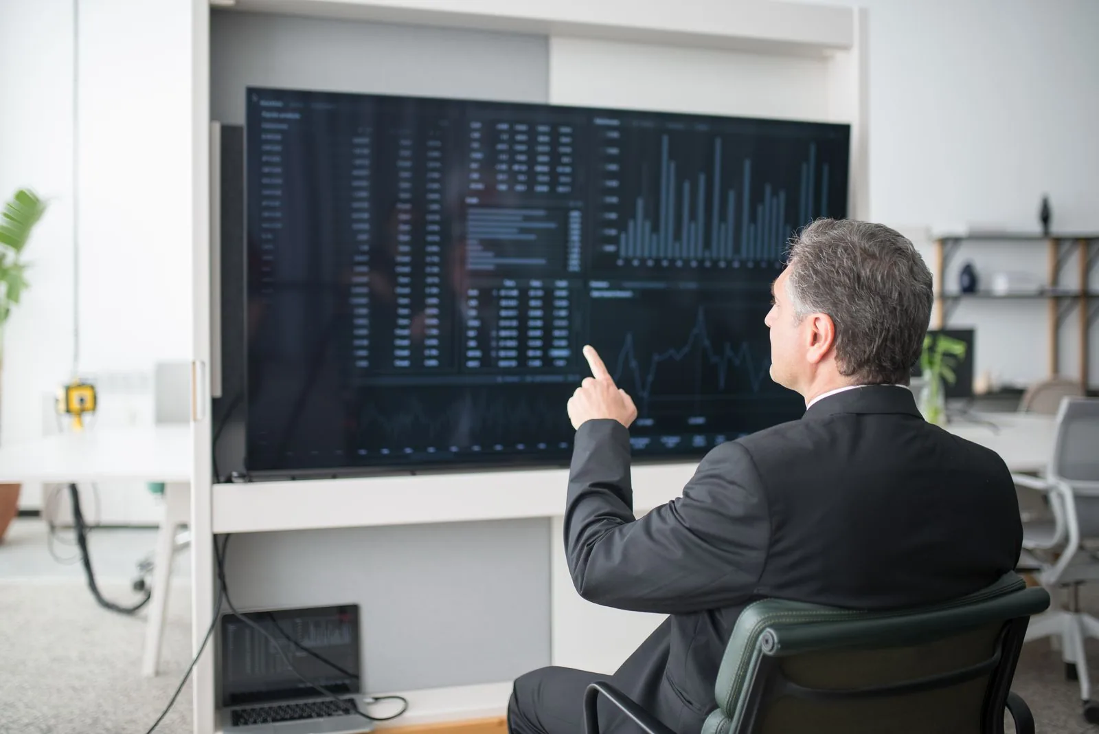 Focused young trader looking at a computer screen in a dark office