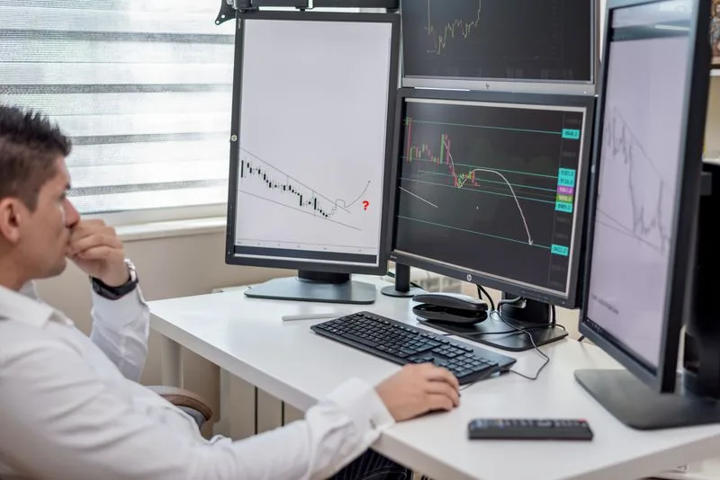 Trader at a multi-screen workstation during an evaluation
